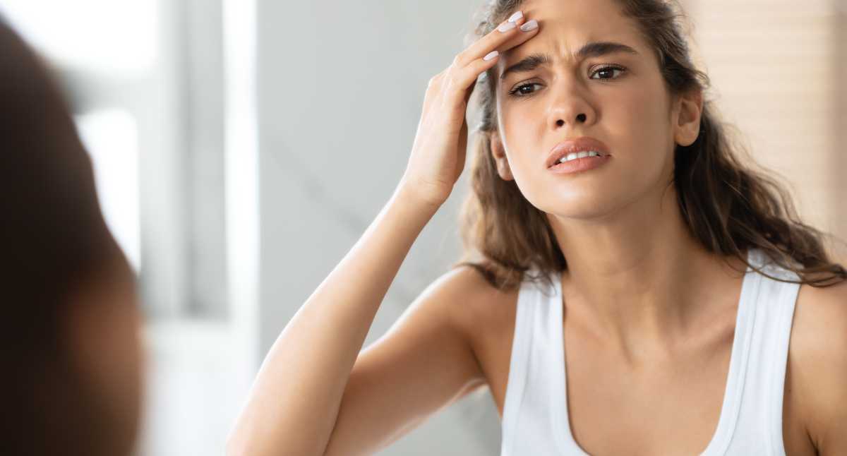Rostro de mujer con piel seca mirándose al espejo